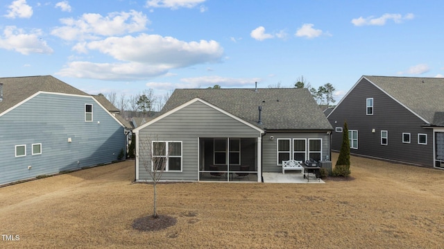 rear view of property with a yard, a patio, a shingled roof, and a sunroom