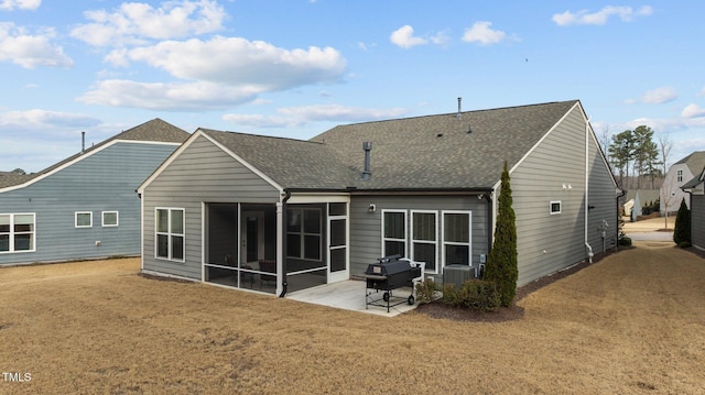 rear view of property with a patio, a yard, roof with shingles, a sunroom, and central AC unit