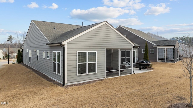 rear view of house with a patio area, a shingled roof, and a yard