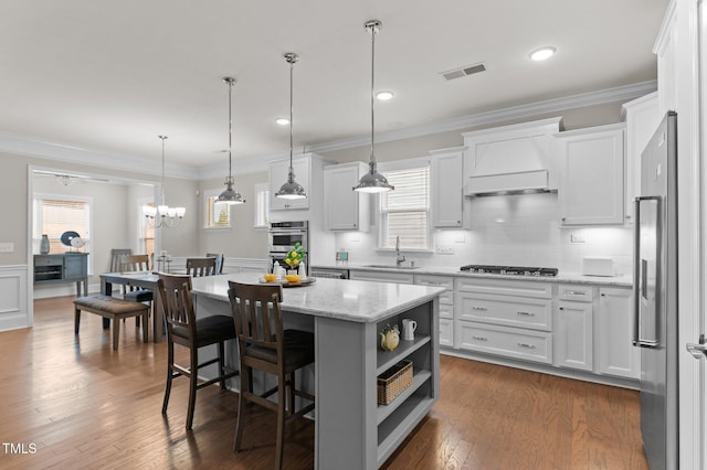 kitchen featuring custom exhaust hood, open shelves, a sink, stainless steel appliances, and a center island