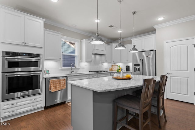 kitchen featuring dark wood-style floors, ornamental molding, a sink, appliances with stainless steel finishes, and tasteful backsplash