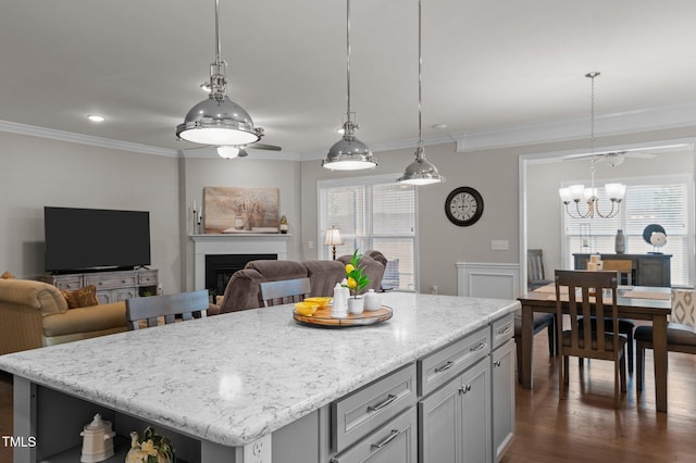 kitchen featuring dark wood-type flooring, a kitchen island, open floor plan, a fireplace, and crown molding