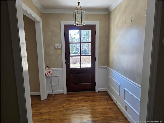 doorway with wood finished floors, wainscoting, and crown molding