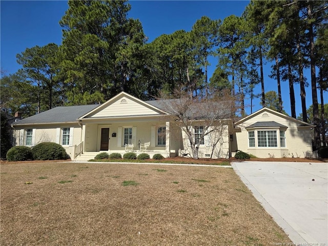 ranch-style house featuring covered porch and a front lawn