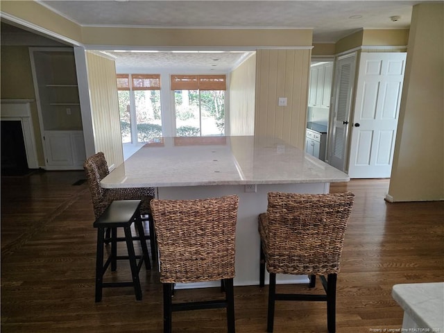 kitchen featuring a kitchen breakfast bar, light stone countertops, a kitchen island, and dark wood-style floors