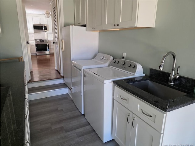 laundry area with dark wood-type flooring, washer and clothes dryer, cabinet space, a ceiling fan, and a sink