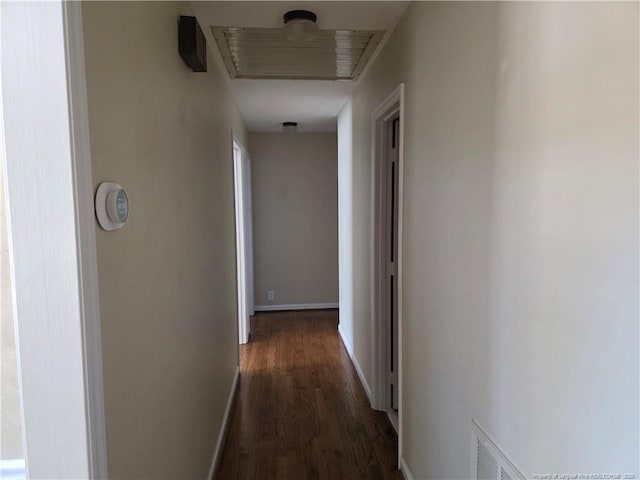 hall with baseboards, visible vents, and dark wood-style flooring