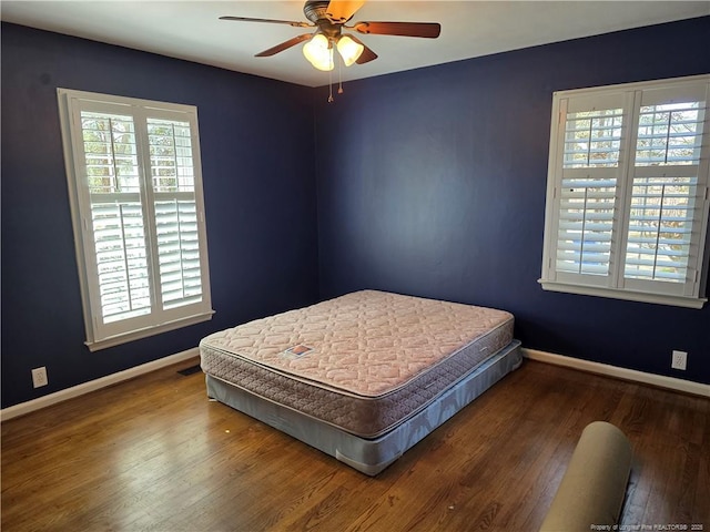 bedroom featuring visible vents, baseboards, wood-type flooring, and a ceiling fan