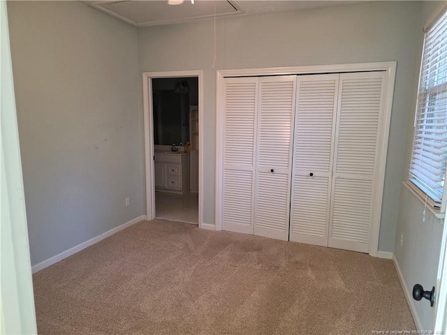 unfurnished bedroom with attic access, a closet, carpet floors, and connected bathroom