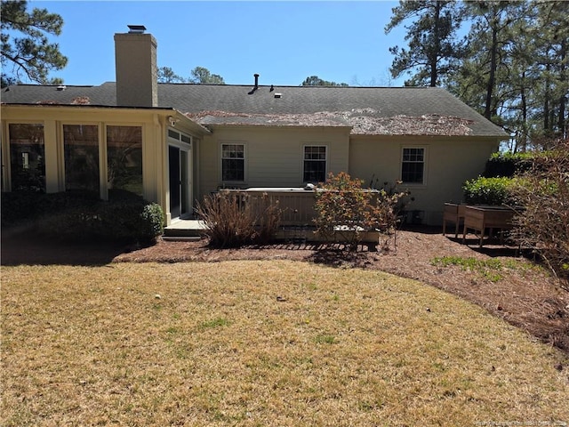 rear view of house with a deck, a lawn, and a chimney