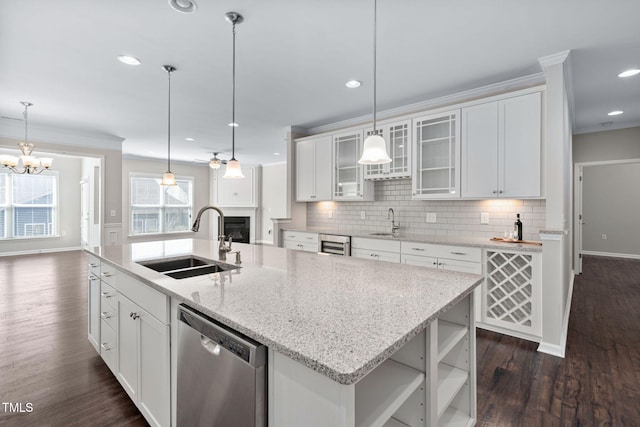 kitchen with backsplash, ornamental molding, stainless steel dishwasher, white cabinets, and a sink