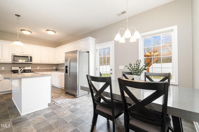 kitchen with a wealth of natural light, visible vents, appliances with stainless steel finishes, white cabinets, and light countertops