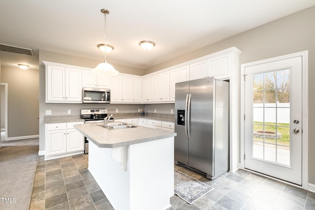 kitchen with a center island with sink, a sink, white cabinetry, stainless steel appliances, and light countertops