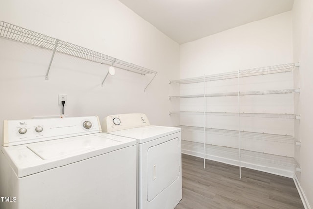 laundry area with washer and dryer, laundry area, baseboards, and light wood-type flooring