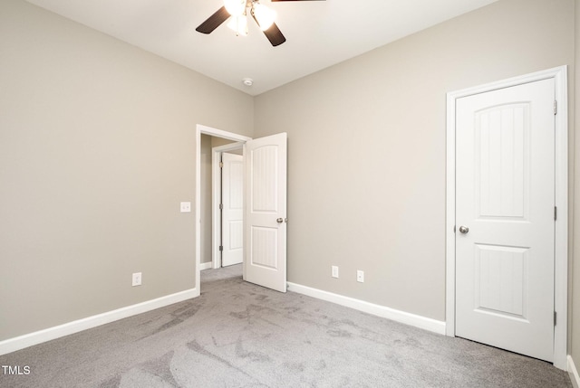 carpeted empty room featuring a ceiling fan and baseboards