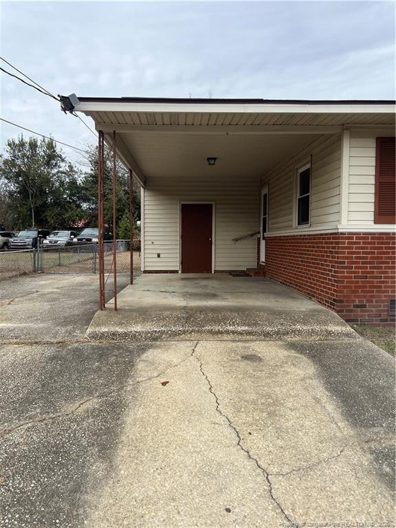 view of vehicle parking featuring concrete driveway, a carport, and fence