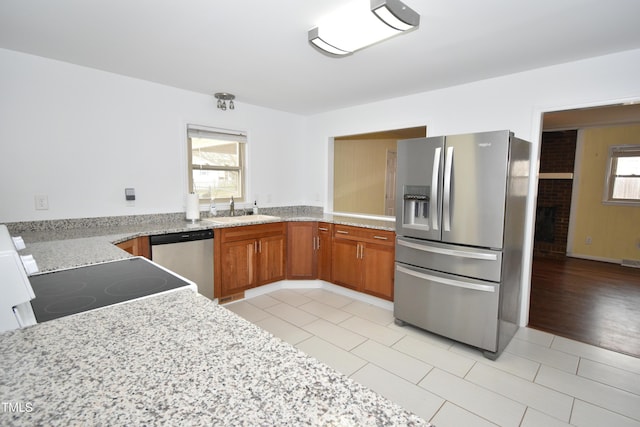 kitchen with light tile patterned floors, brown cabinets, stainless steel appliances, and a sink