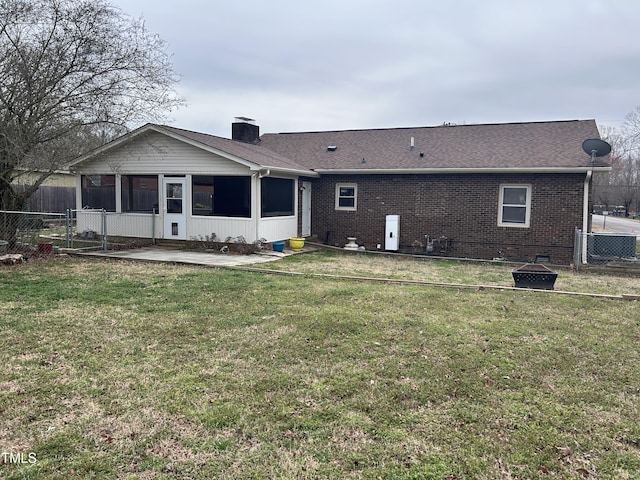 rear view of house featuring brick siding, a lawn, a chimney, and fence