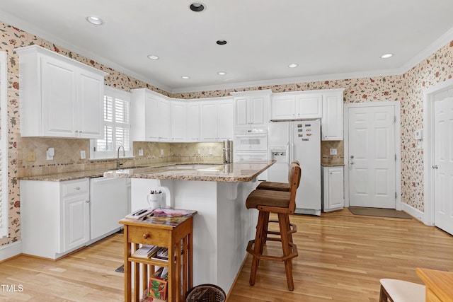 511 Windstream Way, Cary, NC 27518 - kitchen featuring white appliances, crown molding, a sink, light wood-type flooring, and a kitchen bar