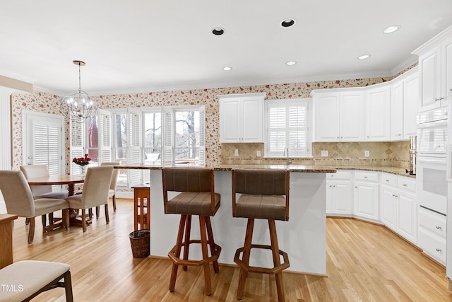 511 Windstream Way, Cary, NC 27518 - kitchen with crown molding, a chandelier, healthy amount of natural light, a breakfast bar, and light wood finished floors