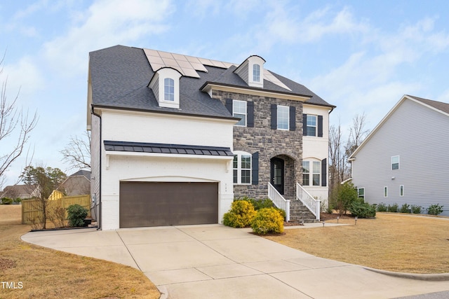 french country style house with a front yard, fence, driveway, solar panels, and a garage