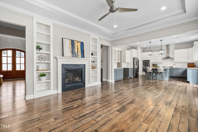 unfurnished living room with french doors, a raised ceiling, dark wood finished floors, and ornamental molding