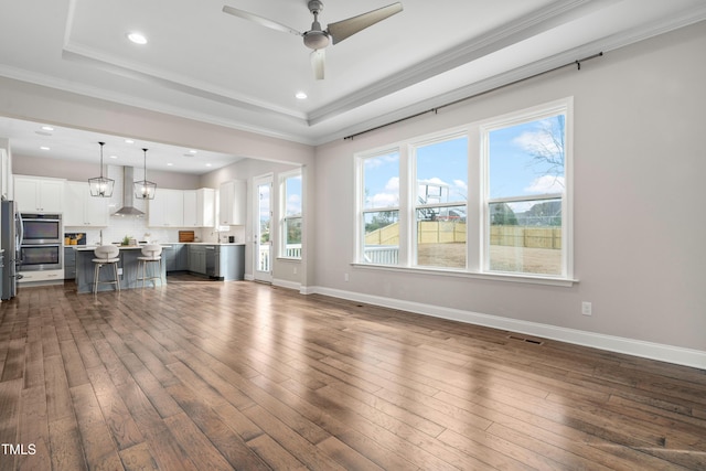 living room with visible vents, dark wood-type flooring, ceiling fan, baseboards, and a raised ceiling