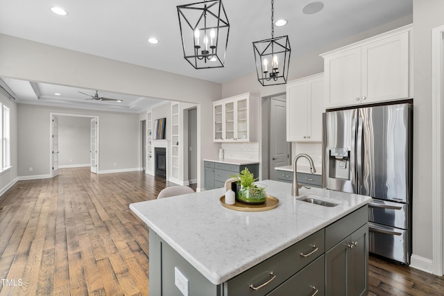 kitchen featuring dark wood-style floors, a sink, white cabinets, a glass covered fireplace, and stainless steel fridge