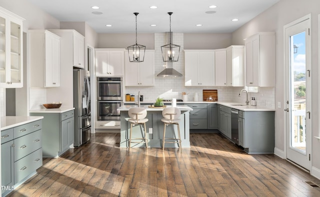 kitchen with visible vents, a kitchen island, a sink, appliances with stainless steel finishes, and a kitchen breakfast bar