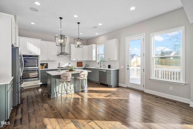 kitchen featuring visible vents, a center island with sink, a kitchen bar, light countertops, and stainless steel appliances