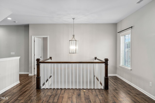 corridor with an upstairs landing, an inviting chandelier, baseboards, and wood finished floors