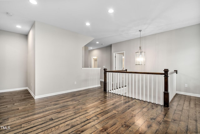 unfurnished room featuring an inviting chandelier, recessed lighting, dark wood-style flooring, and baseboards