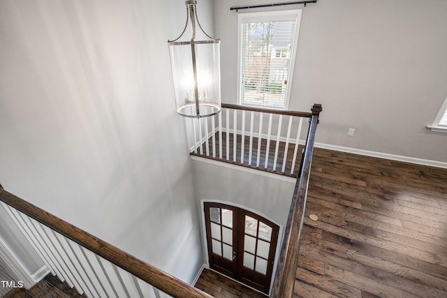 stairs featuring arched walkways, french doors, baseboards, and wood finished floors