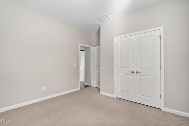 unfurnished bedroom with light carpet, visible vents, a closet, and baseboards