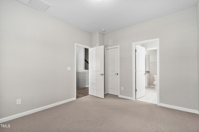 unfurnished bedroom featuring ensuite bath, visible vents, baseboards, and light carpet