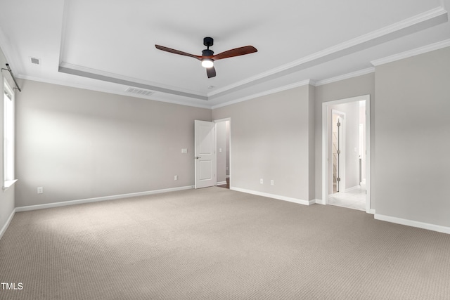 carpeted spare room featuring visible vents, a raised ceiling, baseboards, and crown molding