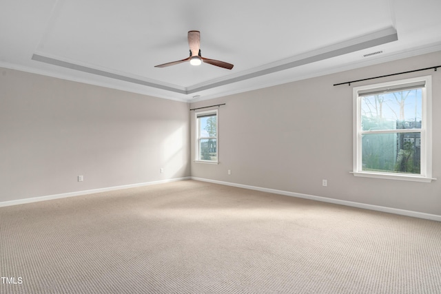 empty room with light carpet, baseboards, crown molding, and a tray ceiling