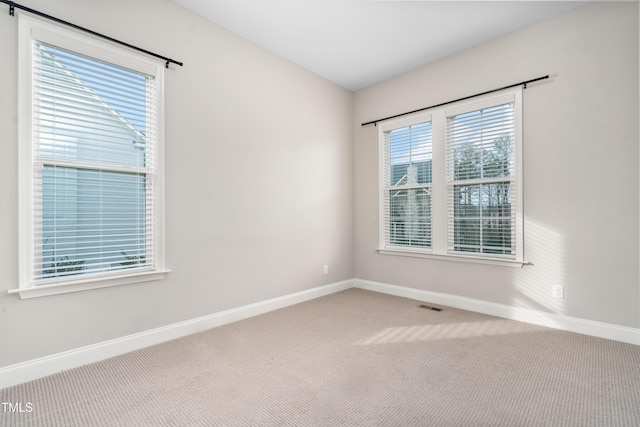 empty room featuring visible vents, baseboards, and carpet