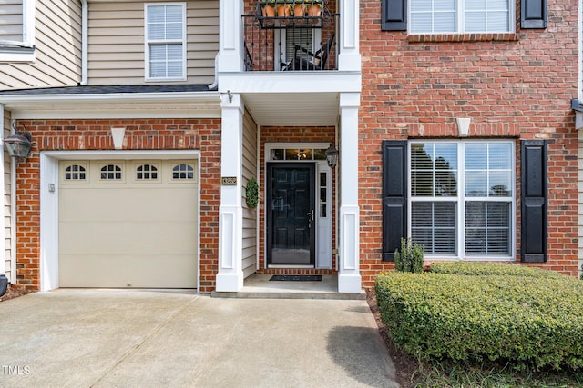 doorway to property featuring brick siding, driveway, and a garage