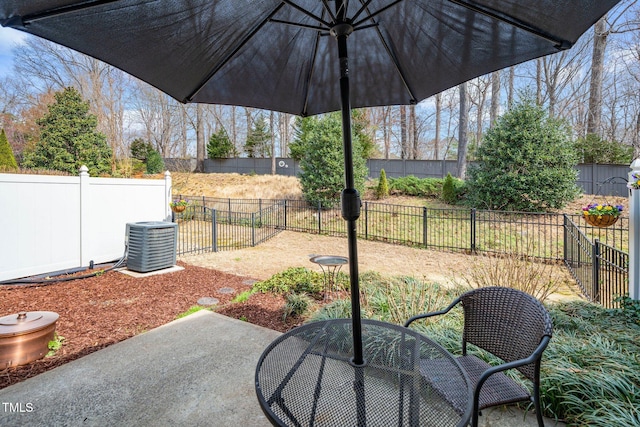 view of patio featuring outdoor dining space, central AC unit, and a fenced backyard