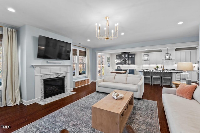 living room with recessed lighting, a notable chandelier, dark wood-style floors, and a fireplace