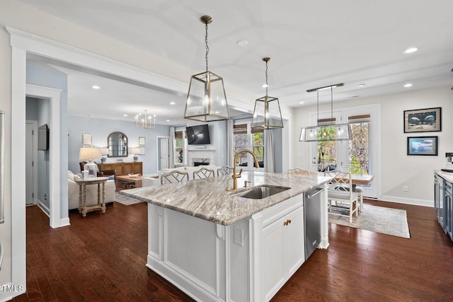 kitchen featuring a fireplace, light stone countertops, dark wood-style flooring, and a sink