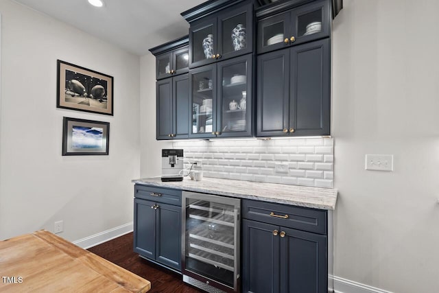 bar with tasteful backsplash, dark wood-type flooring, baseboards, beverage cooler, and a bar