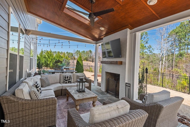 view of patio featuring an outdoor living space with a fireplace, ceiling fan, and fence