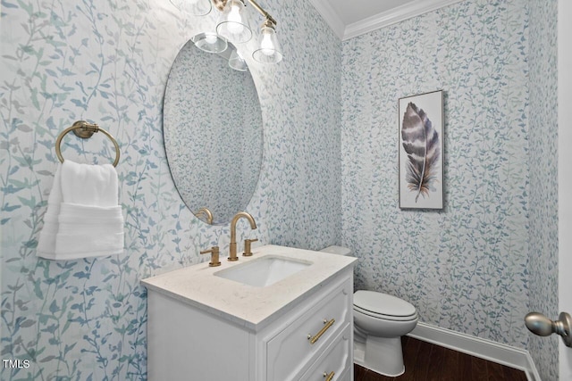 half bathroom with toilet, wood finished floors, crown molding, wallpapered walls, and vanity