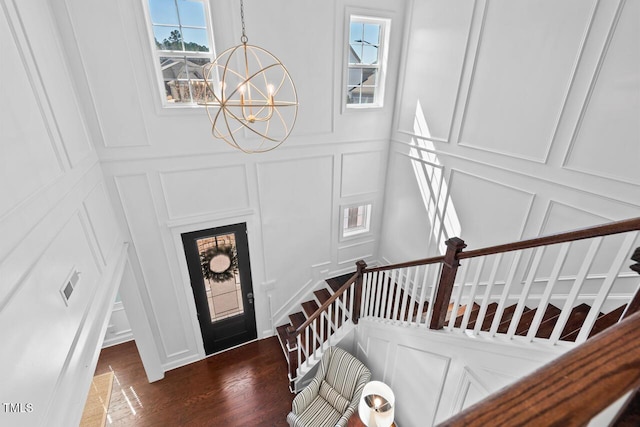 entryway with visible vents, wood finished floors, stairway, an inviting chandelier, and a decorative wall