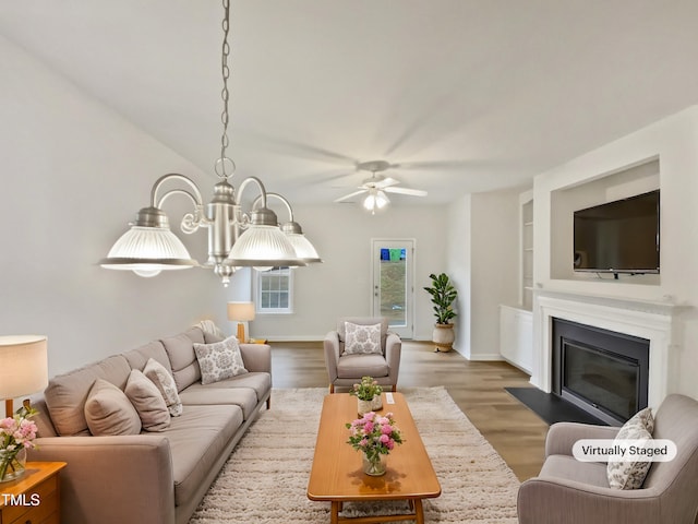 living room with a glass covered fireplace, baseboards, built in features, and wood finished floors