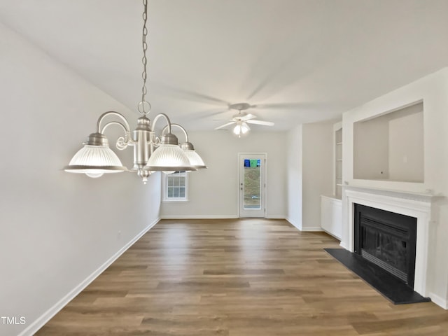 unfurnished living room with a fireplace with raised hearth, baseboards, built in features, ceiling fan with notable chandelier, and wood finished floors