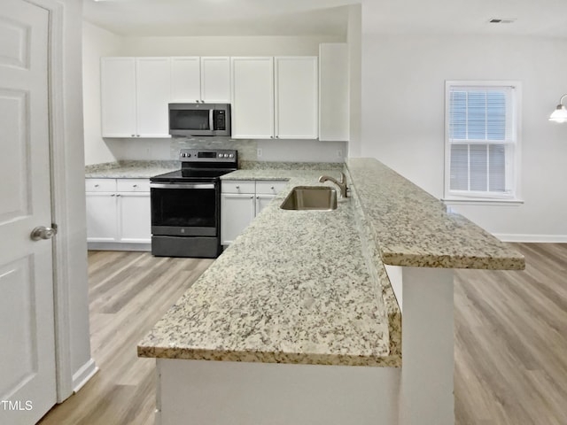 2356 Bay Harbor Dr, Raleigh, NC 27604 - kitchen featuring a peninsula, light stone counters, appliances with stainless steel finishes, and a sink