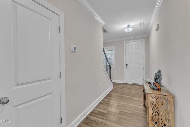 hall with light wood finished floors, visible vents, baseboards, stairs, and ornamental molding